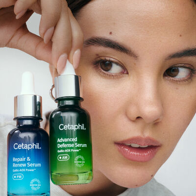 Close-up de uma mulher segurando dois frascos de s&eacute;rum Cetaphil ao lado do rosto; um frasco azul &ldquo;Repair & Renew Serum (PM)&rdquo; e um frasco verde &ldquo;Advanced Defense Serum (AM)&rdquo;.