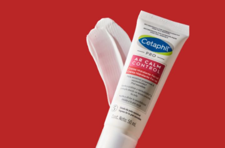 Creme Hidratante Facial Cetaphil PRO AR Calm Control em um fundo vermelho com um espiral do creme.