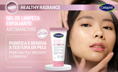 Uma mulher asiática com cabelo escuro e pele clara olha para a câmera com uma expressão suave. Sua mão direita está levemente levantada perto do rosto. No centro da imagem, um tubo de gel de limpeza esfoliante branco e rosa da Cetaphil está em destaque sobre um pedestal branco. O texto "NOVO HEALTHY RADIANCE" e "GEL DE LIMPEZA ESFOLIANTE ANTIMANCHAS" aparece na parte superior. Há também um selo "MADE IN KOREA" e a frase "PURIFICA E RENOVA A TEXTURA DA PELE PARA UMA PELE RADIANTE E LUMINOSA".