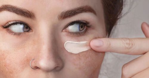 Mulher branca aplicando creme noturno Cetaphil Healthy Renew para cuidar da pele do rosto com hiperpigmentação.