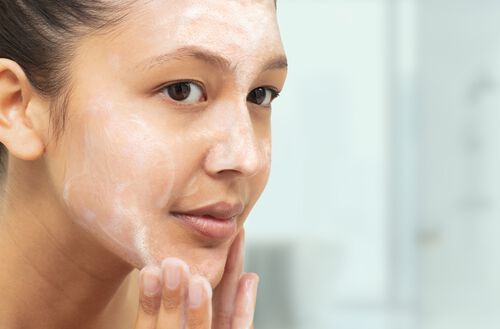 Mulher latina lavando a pele do rosto.