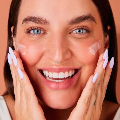 Influencer Bruna Unzueta (@boounzueta) sorrindo e passando creme para rugas e linhas finas.