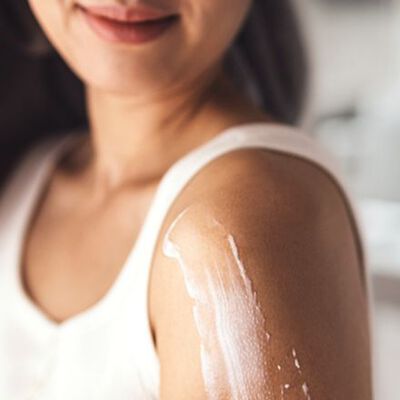 Creme com ceramidas aplicado em ombro de mulher.