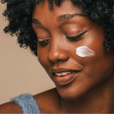 Mulher de pele negra com creme hidratante com niacinamida no rosto. 