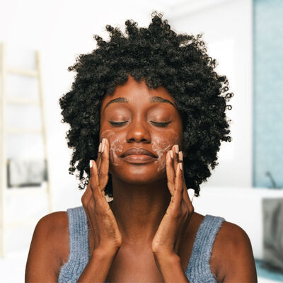 Mulher de pele negra com creme hidratante com niacinamida no rosto.